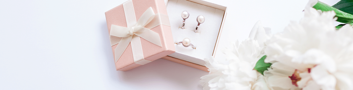 pear earrings and a ring in a pink gift box with a ribbon sitting next to white flowers